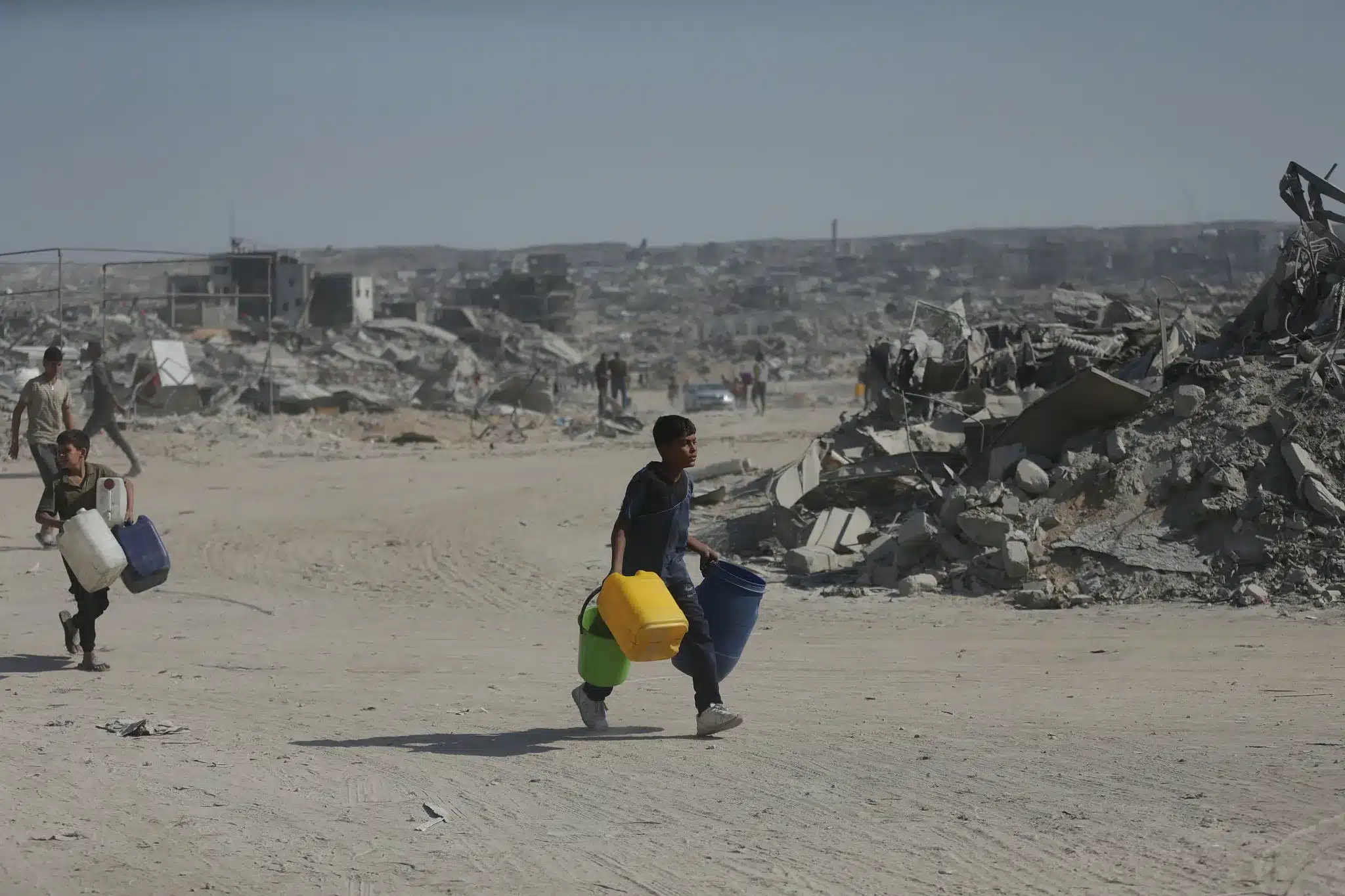 Niños cargan jarras en busca de agua entre los escombros de Jabalia, norte de Gaza, 16 de octubre de 2025. (Yousef Zaanoun)