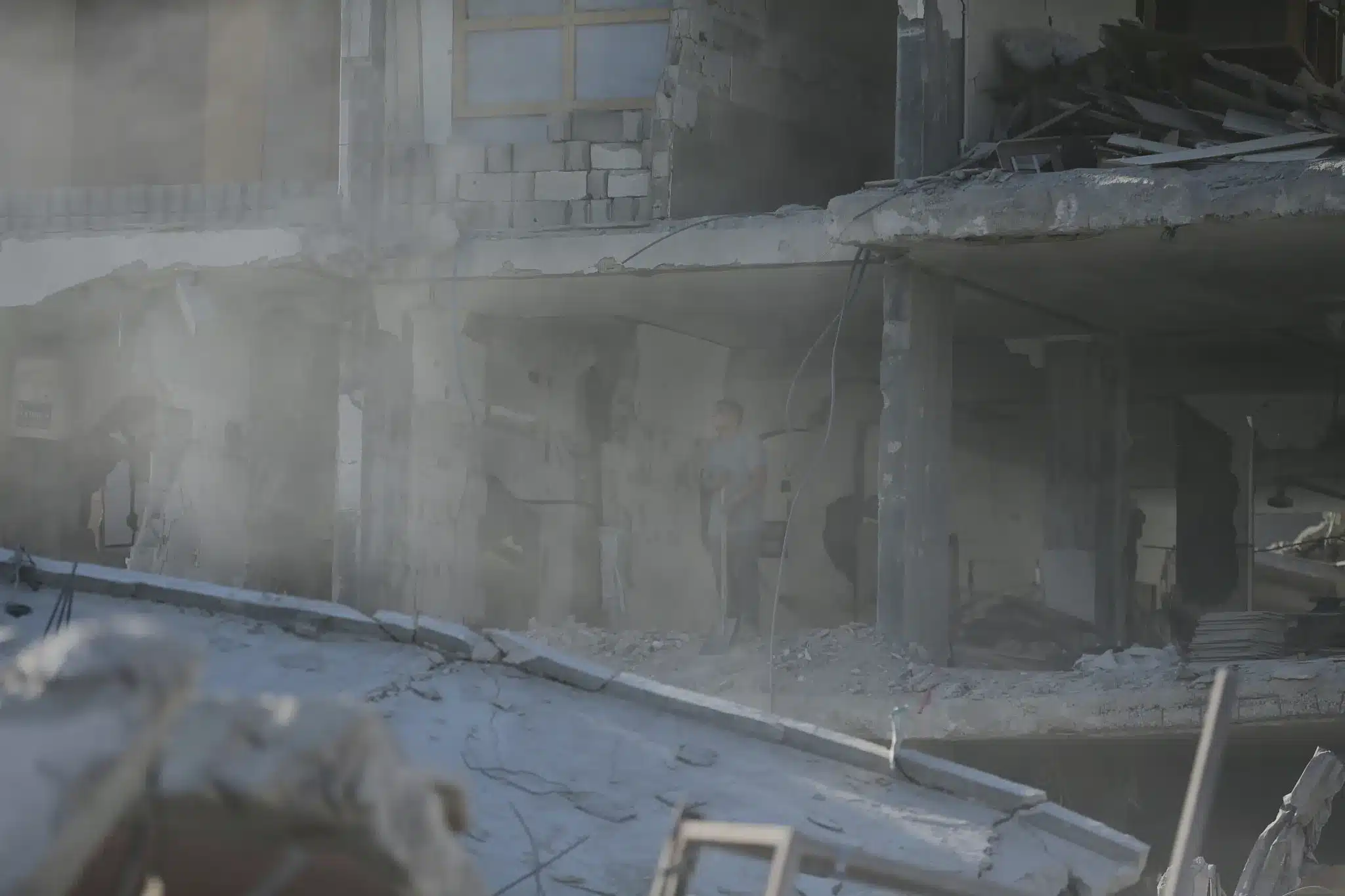 El polvo llena el aire mientras un hombre se encuentra dentro de los restos destrozados de su casa, sosteniendo una pala en medio de la destrucción, Sheikh Radwan, ciudad de Gaza, 16 de octubre de 2025. (Yousef Zaanoun)