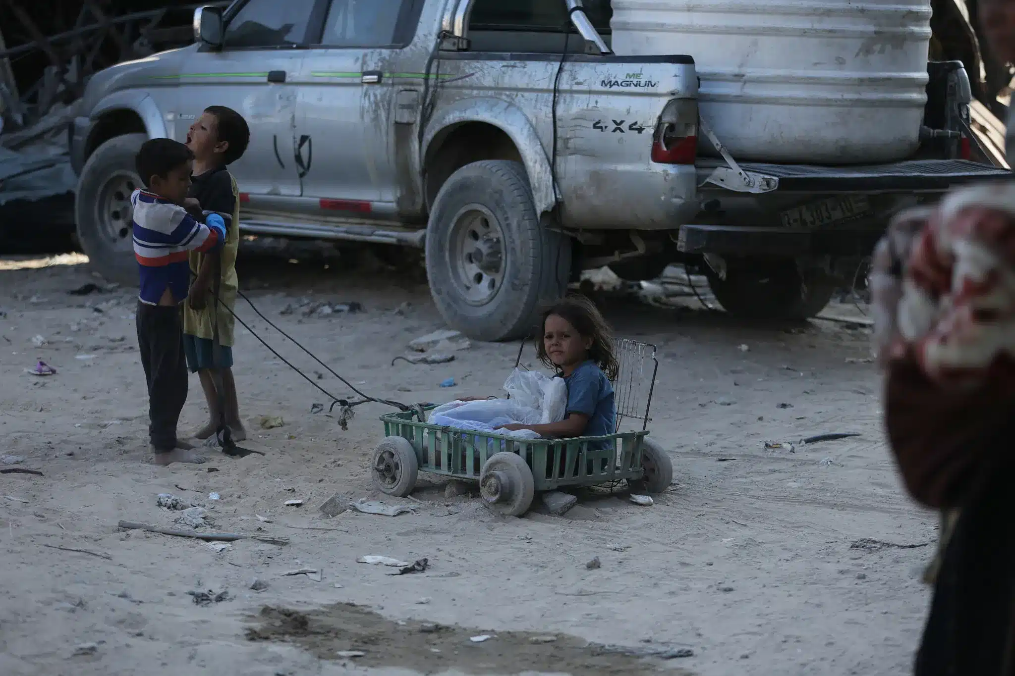 Niños tiran de un carro improvisado por las polvorientas calles de Jabalia, al norte de Gaza, llevando a una niña pequeña y lo que queda de sus pertenencias, 16 de octubre de 2025. (Yousef Zaanoun)